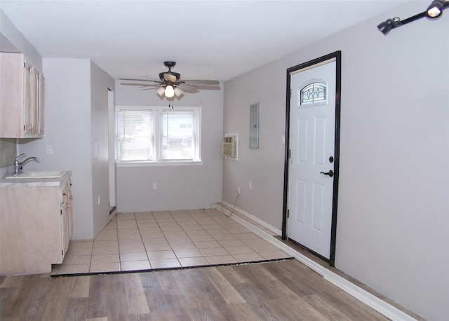 interior space with a ceiling fan, light wood-style flooring, a sink, electric panel, and light countertops