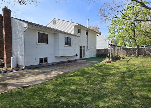 rear view of property with central air condition unit, roof with shingles, fence, a yard, and a patio
