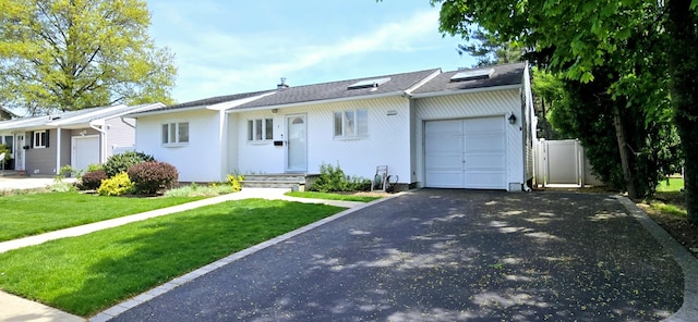 ranch-style house with a front lawn, aphalt driveway, and a garage
