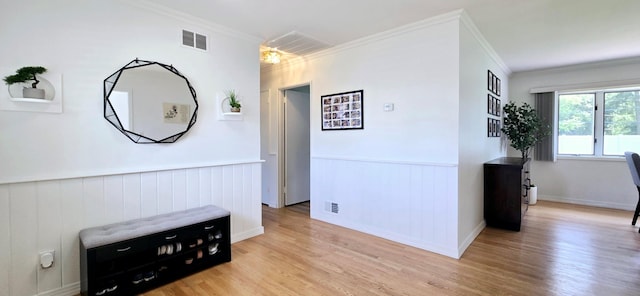 corridor featuring crown molding, visible vents, and a wainscoted wall