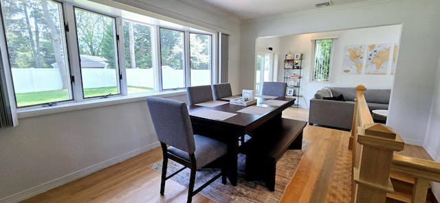 dining area featuring crown molding, light wood-style floors, visible vents, and baseboards