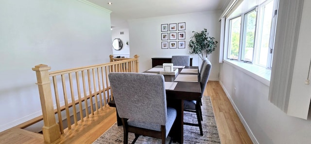 dining room with wood finished floors, baseboards, and ornamental molding