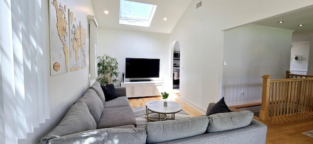 living room with vaulted ceiling with skylight, wood finished floors, visible vents, recessed lighting, and arched walkways