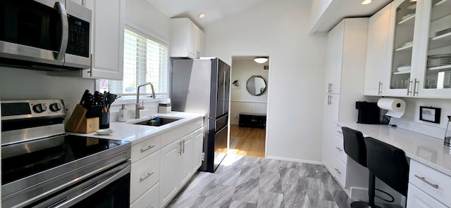 kitchen featuring a sink, stainless steel appliances, light countertops, and white cabinets