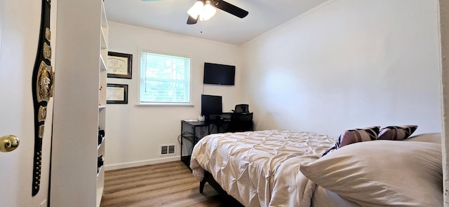 bedroom with wood finished floors, visible vents, crown molding, a ceiling fan, and baseboards