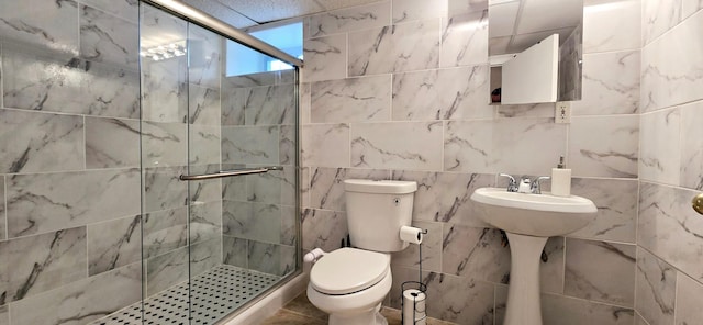 full bathroom with tile walls, toilet, and a stall shower