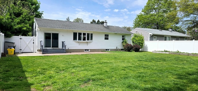 rear view of house with a yard, a chimney, fence, and a gate