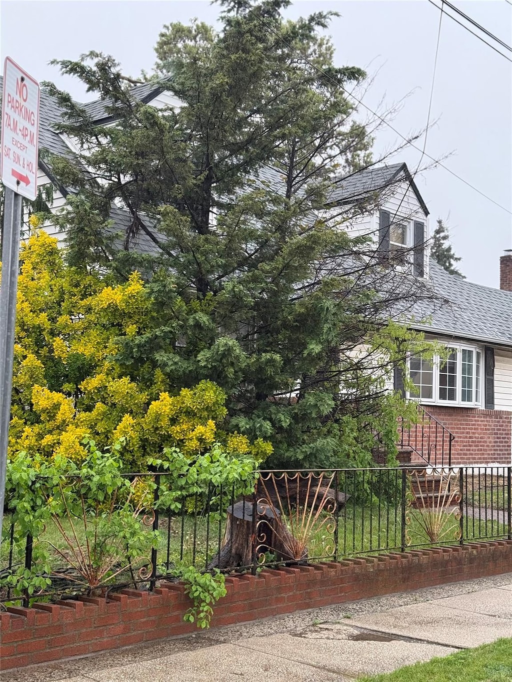 view of side of property featuring fence, brick siding, a shingled roof, and a chimney