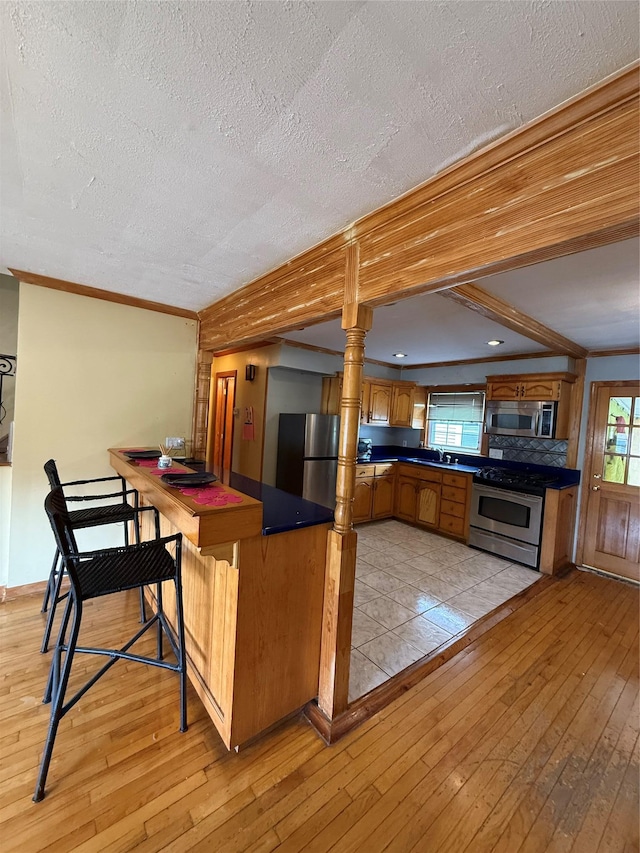 163 E Hawthorne Ave, Valley Stream, NY 11580 - kitchen featuring stainless steel appliances, dark countertops, light wood-style flooring, healthy amount of natural light, and a textured ceiling