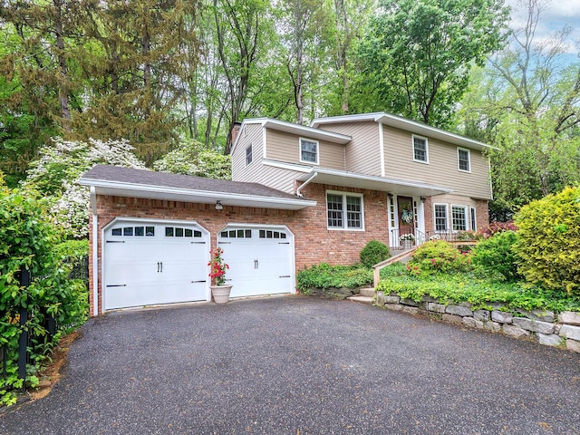 traditional-style house featuring an attached garage, brick siding, and driveway