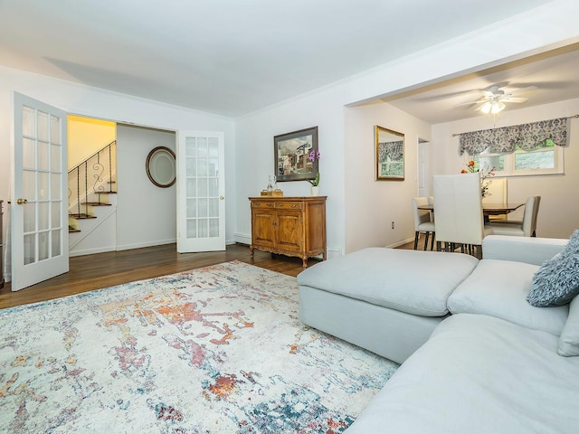 living area with french doors, baseboards, ceiling fan, stairs, and wood finished floors