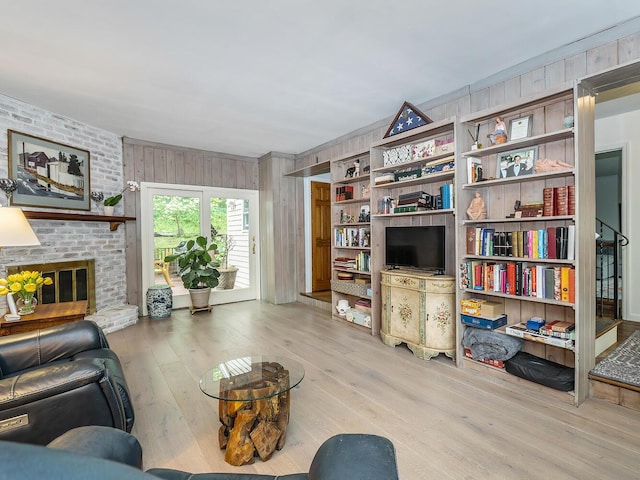 living area featuring hardwood / wood-style flooring, wooden walls, and a fireplace