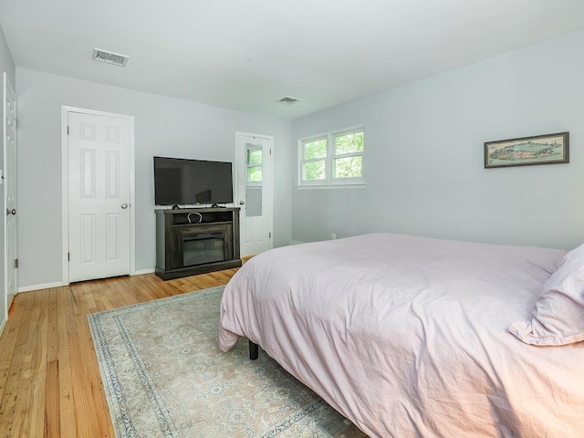 bedroom with baseboards, hardwood / wood-style floors, and visible vents
