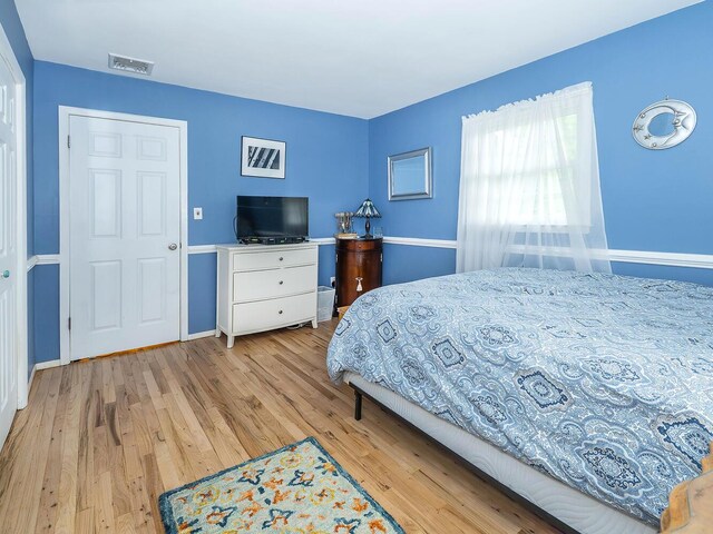 bedroom with baseboards, light wood-style flooring, and visible vents