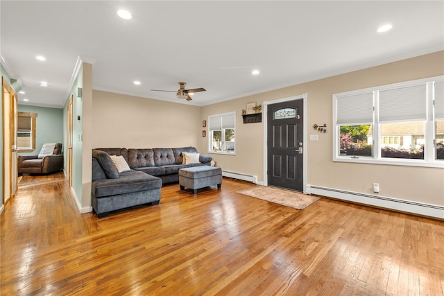 living area with ceiling fan, crown molding, light wood-type flooring, and a baseboard heating unit