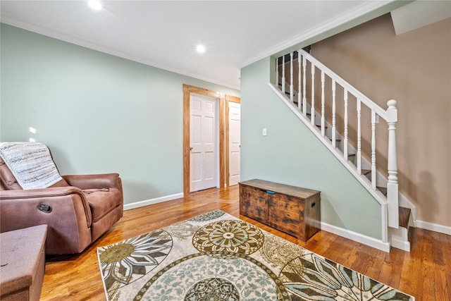 living room with stairway, crown molding, baseboards, and wood finished floors