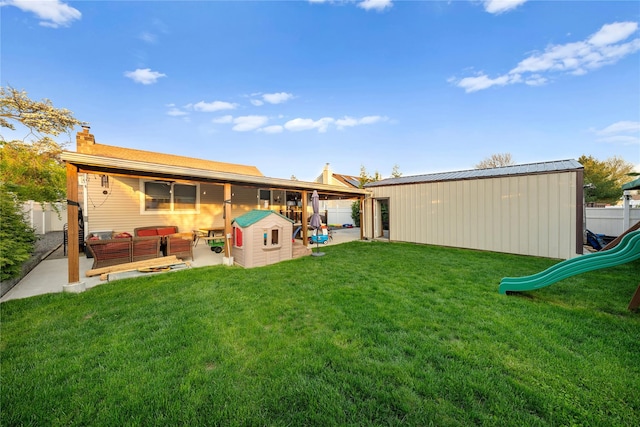 rear view of house featuring a playground, a chimney, a lawn, an outdoor hangout area, and a patio area