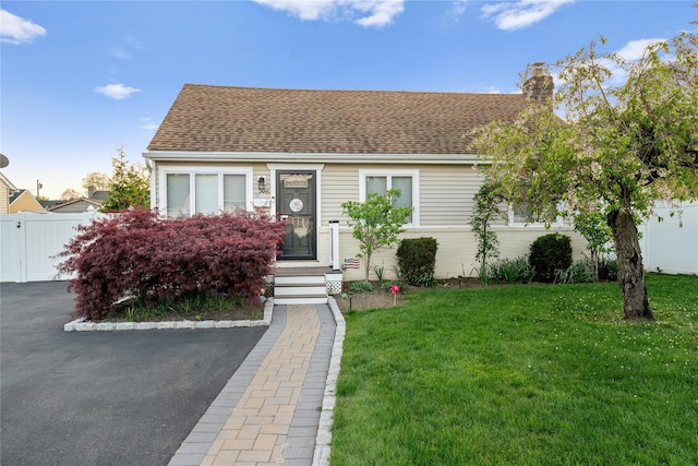 view of front of property with a chimney, a front lawn, and fence