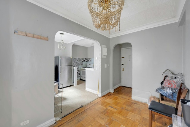 hallway with a chandelier, arched walkways, crown molding, baseboards, and a textured ceiling