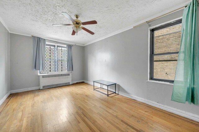 empty room with radiator, wood finished floors, a textured ceiling, ceiling fan, and crown molding