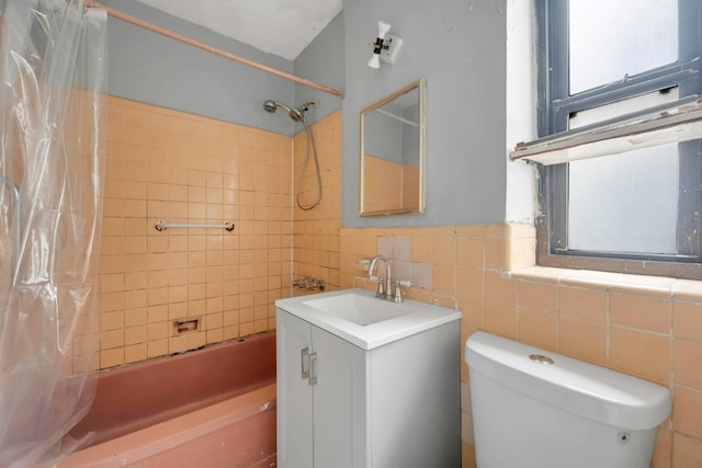 full bathroom with toilet, shower / tub combo, vanity, tile walls, and a wainscoted wall