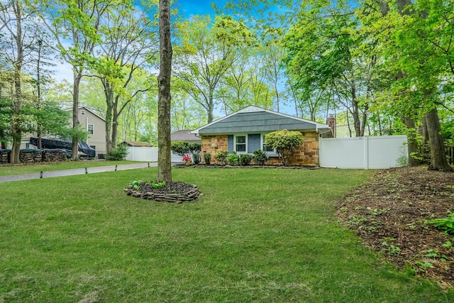 ranch-style home featuring stone siding, fence, and a front yard