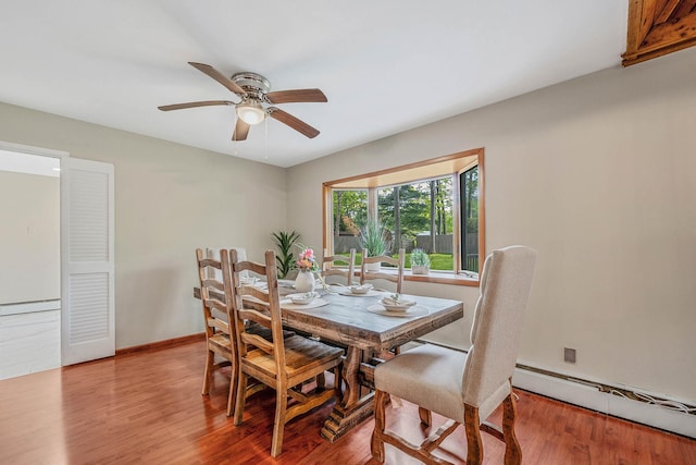 dining room with a ceiling fan, a baseboard radiator, baseboards, and wood finished floors