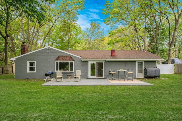 rear view of house featuring fence, heating fuel, a chimney, and a lawn