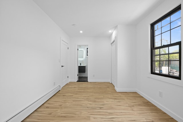spare room with a baseboard heating unit, light wood-style floors, recessed lighting, and baseboards