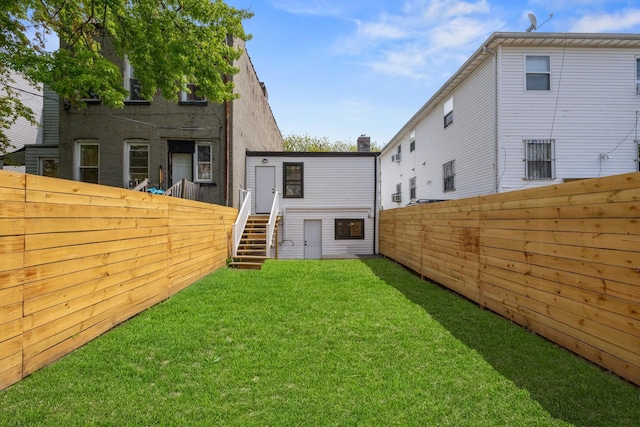 back of house featuring a yard and a fenced backyard