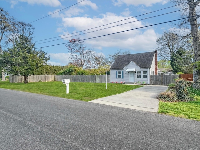view of front of home featuring a front lawn, a chimney, fence, and driveway