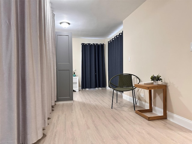 hall featuring light wood-style flooring and baseboards