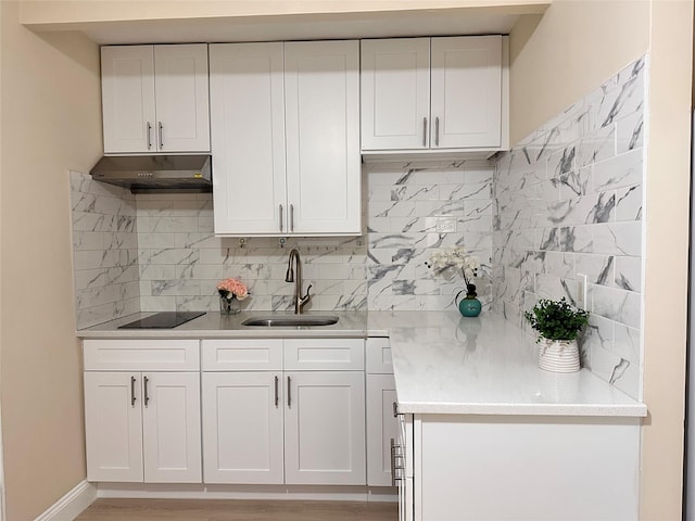 kitchen featuring under cabinet range hood, a sink, backsplash, black electric stovetop, and light countertops
