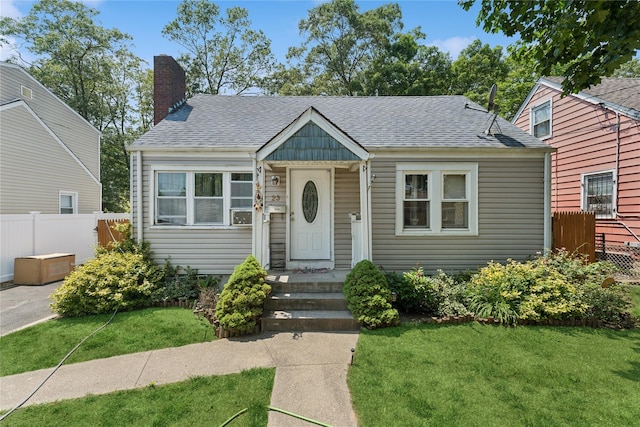23 Wagner Ave, Roosevelt, NY 11575 - bungalow-style home with a chimney and roof with shingles