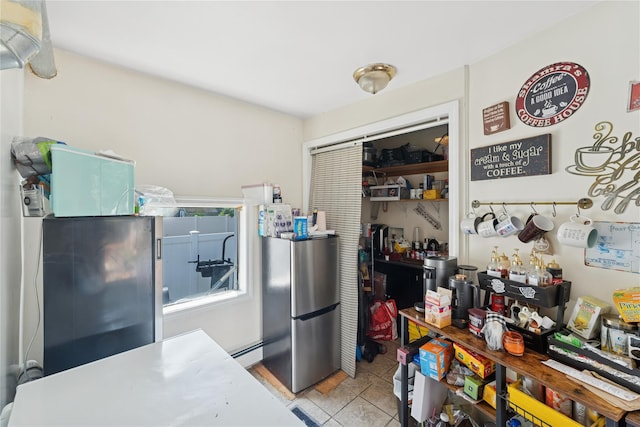 23 Wagner Ave, Roosevelt, NY 11575 - kitchen featuring freestanding refrigerator, a baseboard heating unit, and tile patterned flooring