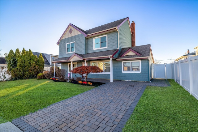 view of front facade featuring a fenced backyard, a shingled roof, a front lawn, and a chimney