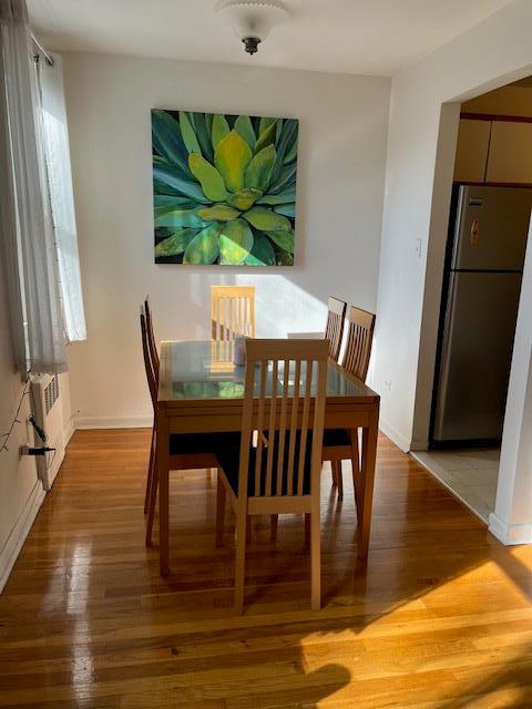 dining room featuring a wealth of natural light, wood finished floors, baseboards, and radiator heating unit