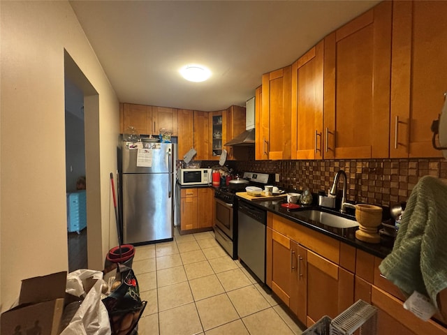 kitchen with a sink, extractor fan, brown cabinetry, backsplash, and appliances with stainless steel finishes