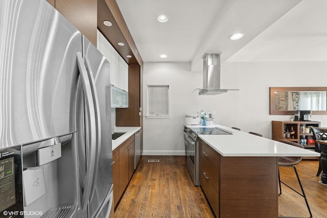 79 Sands Point Rd, Port Washington, NY 11050 - kitchen with a peninsula, a breakfast bar area, recessed lighting, ventilation hood, and appliances with stainless steel finishes
