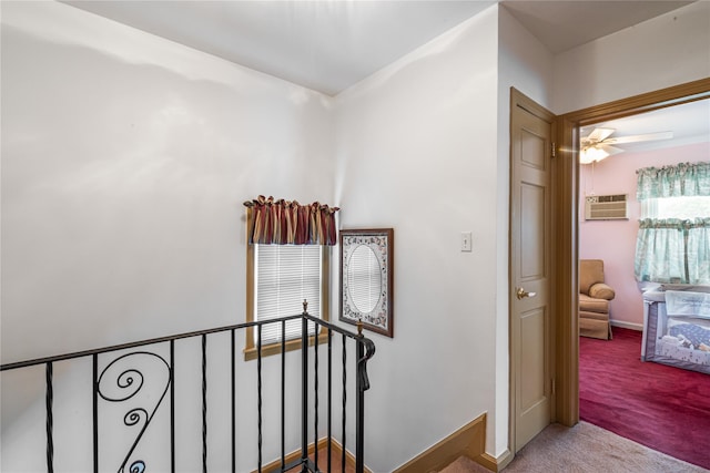 stairs with a wall mounted AC, carpet floors, baseboards, and a ceiling fan