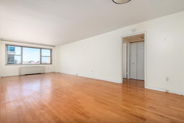 70-20 108th St Unit 15A, Forest Hills, NY 11375 - empty room with light wood-style flooring, baseboards, and radiator heating unit