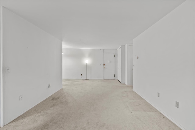 empty room featuring light colored carpet and baseboards