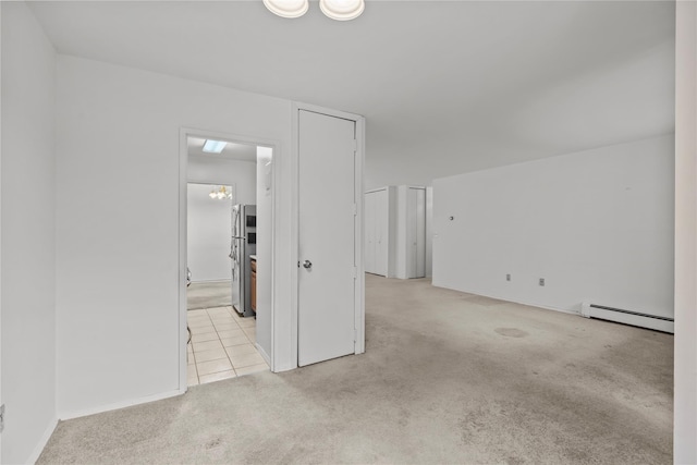 tiled spare room with a baseboard heating unit and carpet flooring