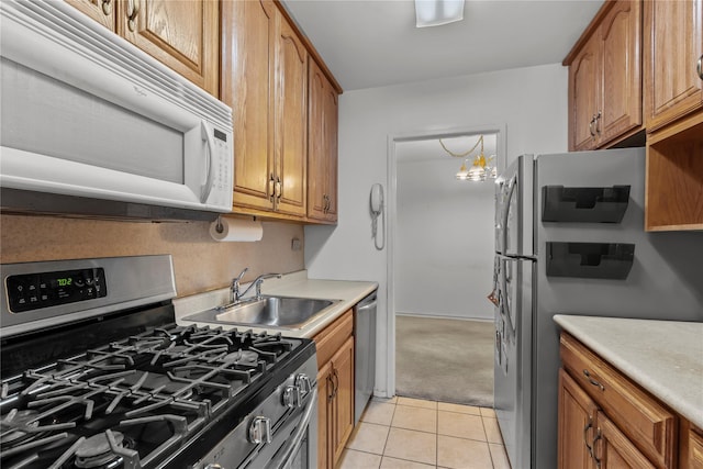 kitchen featuring stainless steel appliances, light tile patterned floors, a sink, brown cabinets, and light countertops