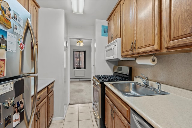 kitchen with a sink, stainless steel appliances, a baseboard heating unit, light countertops, and light tile patterned flooring