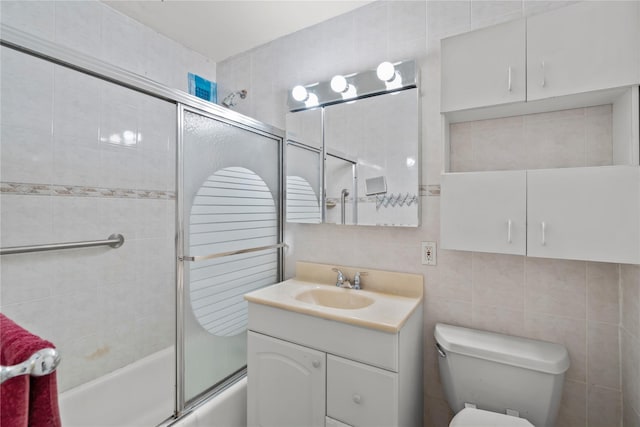 full bathroom with tile walls, enclosed tub / shower combo, toilet, vanity, and tasteful backsplash