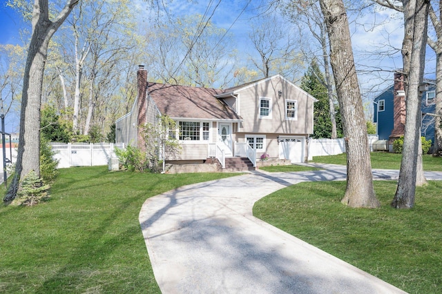 tri-level home featuring a garage, a chimney, fence, concrete driveway, and a front yard