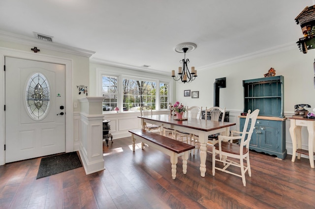 dining space featuring dark wood finished floors, a chandelier, visible vents, and ornamental molding