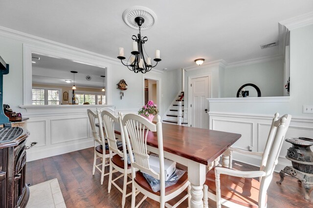 dining room featuring visible vents, a decorative wall, wainscoting, and ornamental molding