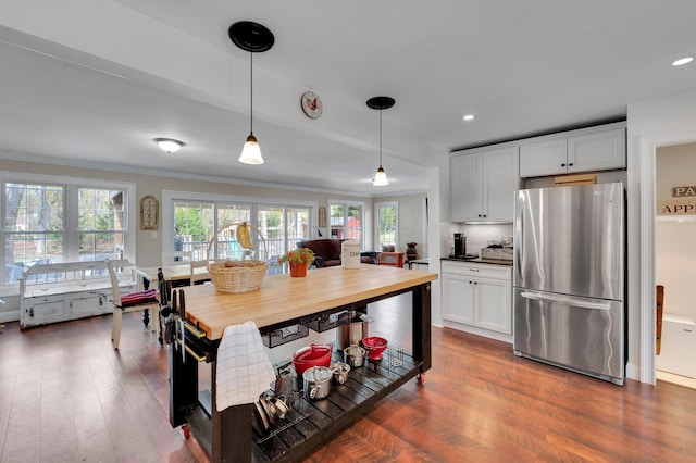 kitchen with hanging light fixtures, freestanding refrigerator, white cabinets, dark wood finished floors, and ornamental molding